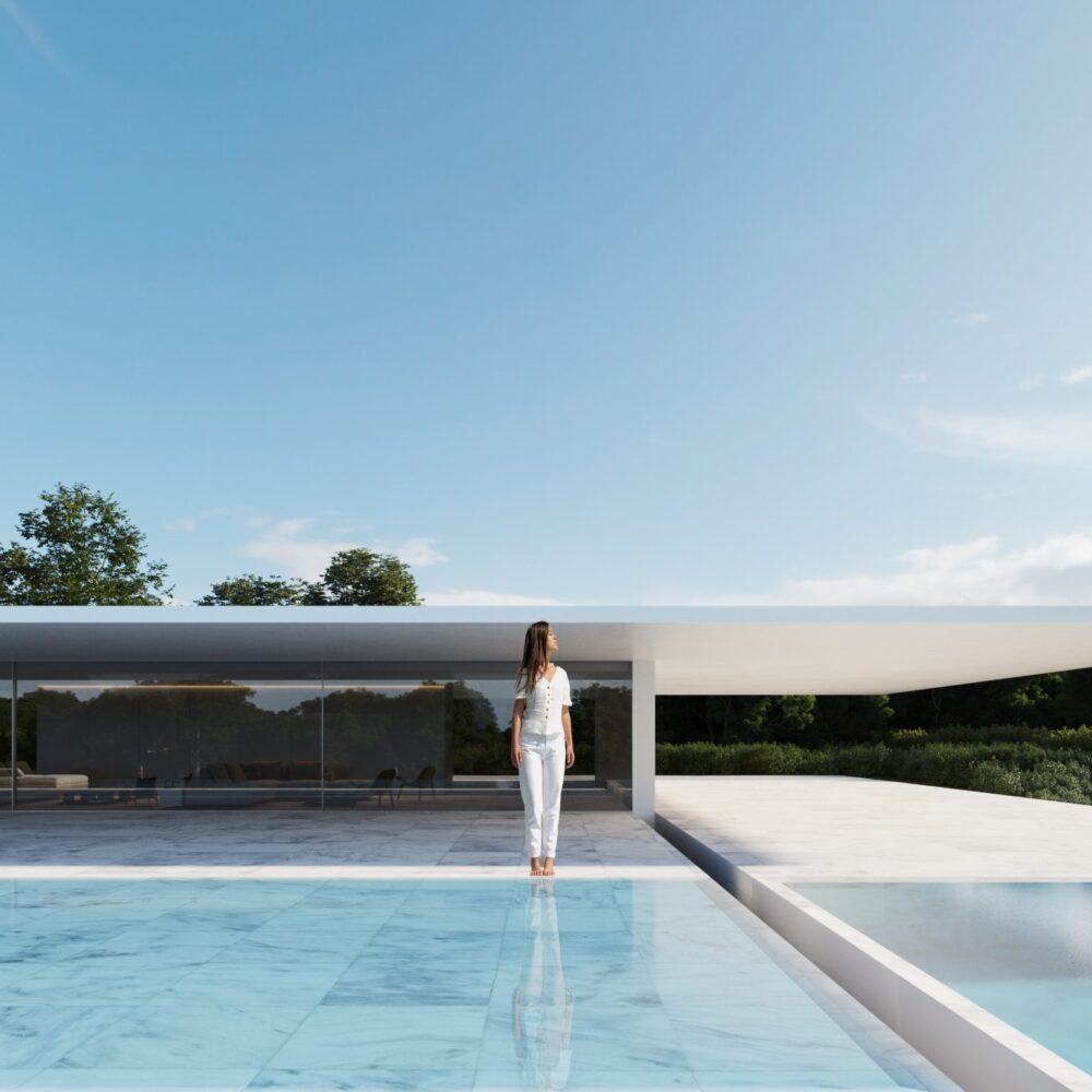 Mujer en Villa 46, edificio moderno con fachada de cristal y piscina de mármol azul en Sotogrande, rodeado de árboles.