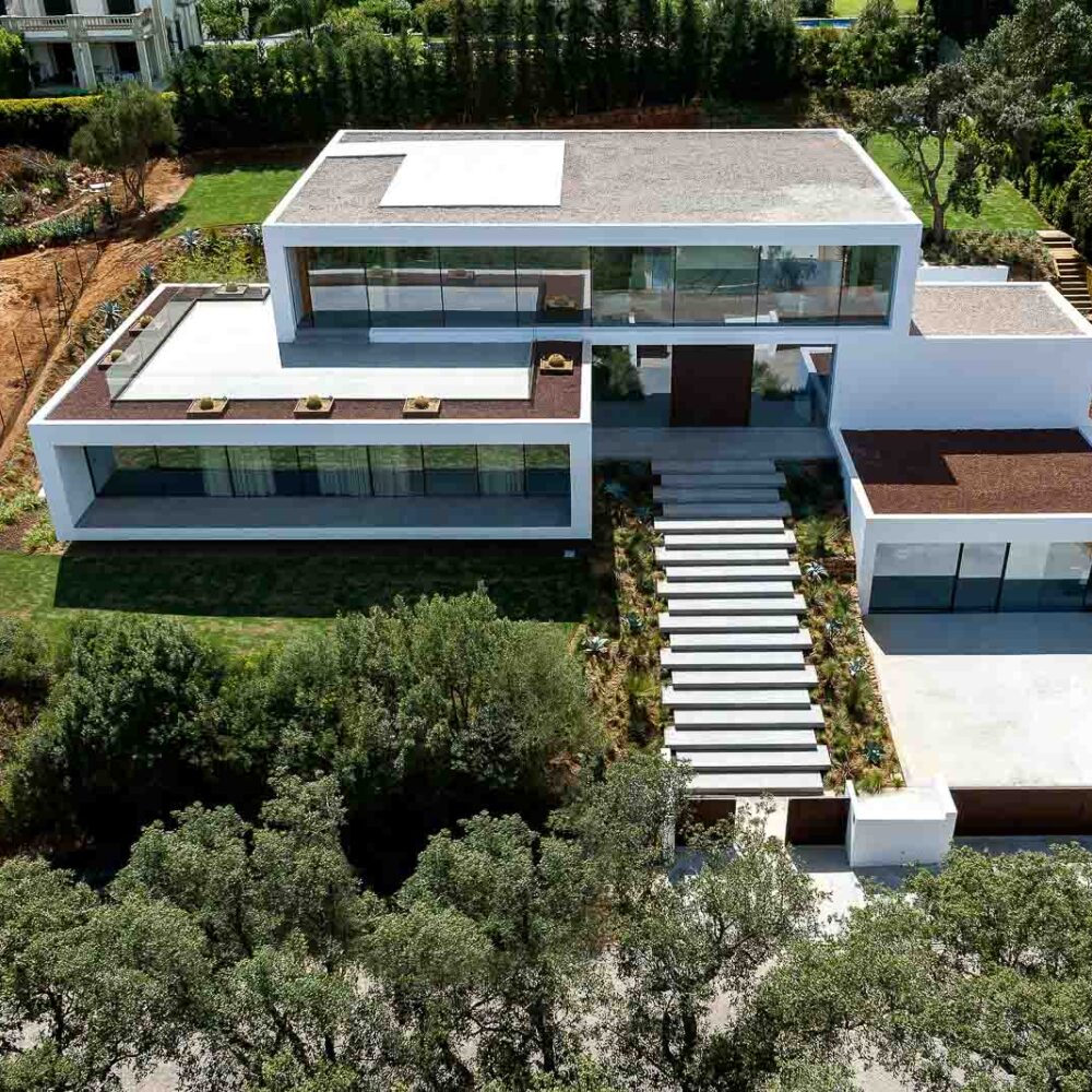 Aerial view of Villa 93, a modern luxury mansion with white facades, large windows, and landscaped gardens.