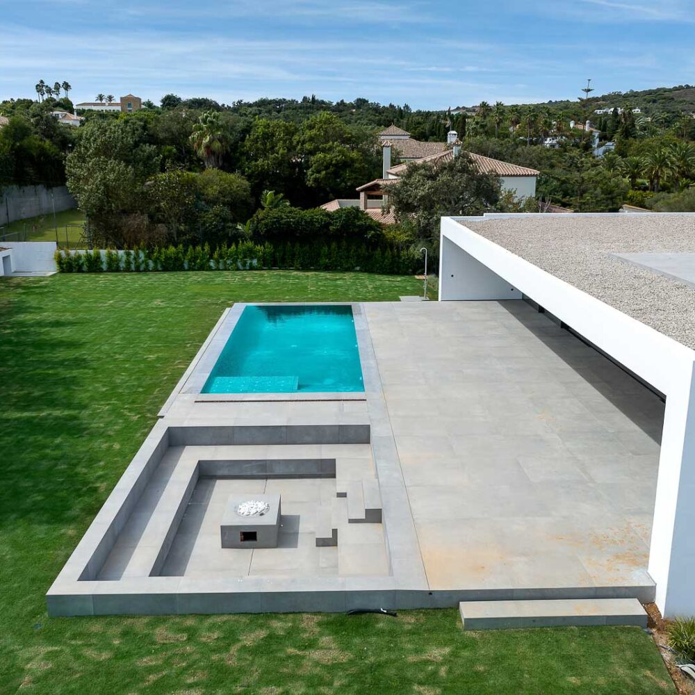 Moderna villa de lujo con piscina, patio, fogata y gran jardín verde.