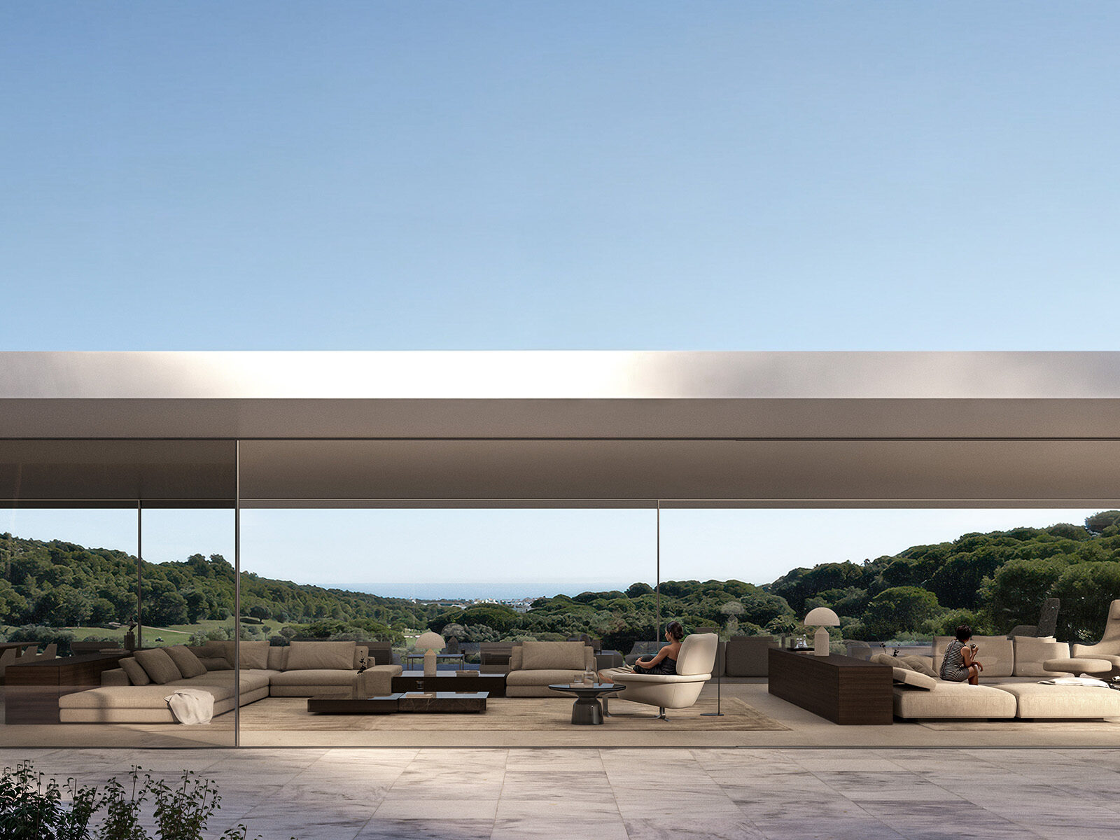 Sotogrande living space with modern sofas, floor-to-ceiling glass, and a panoramic view of lush green hills and the sea.