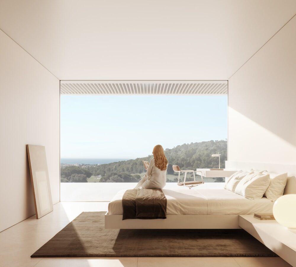 Modern bedroom at Cork Oak Mansion with a woman on a bed admiring the panoramic view of hills and coastline.