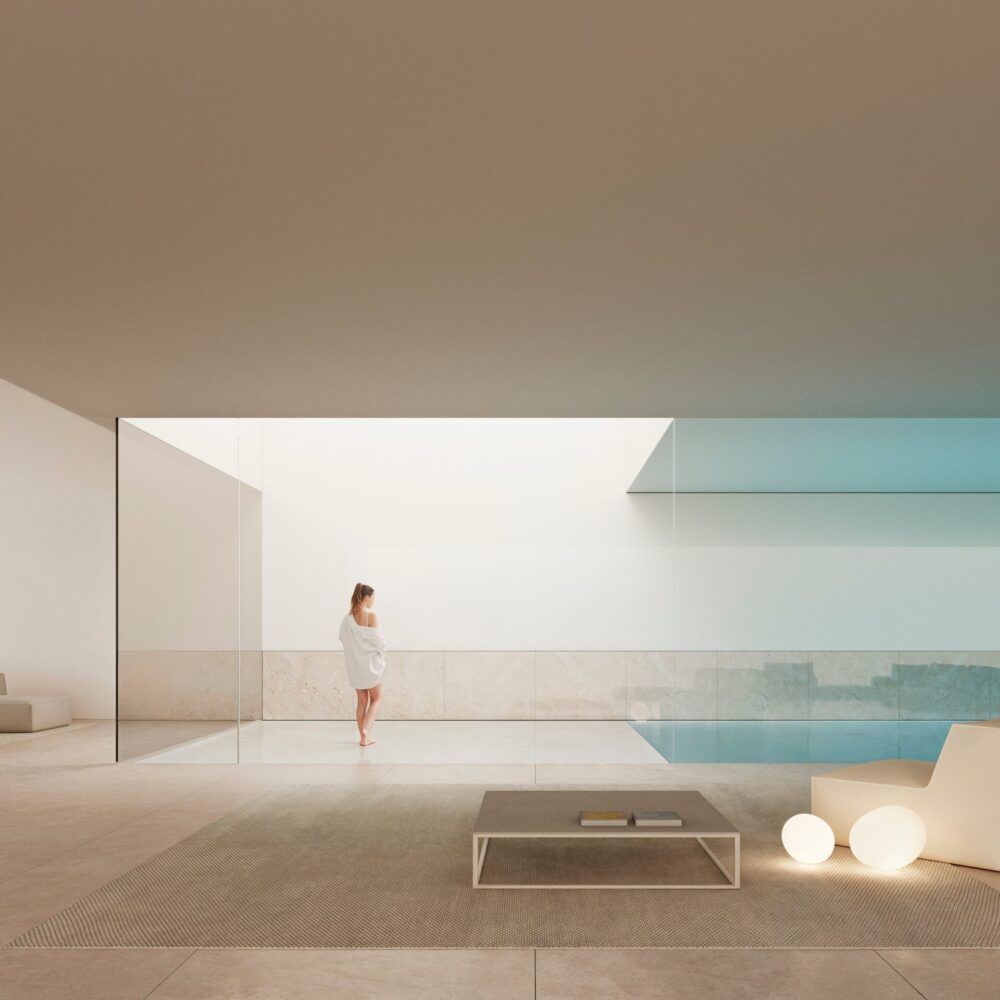 Modern luxury villa living room with a woman, minimalist furniture, and a tranquil pool view.